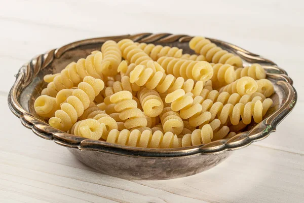 Rå pasta Fusilli bucati på grått trä — Stockfoto