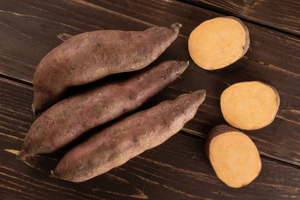 Verse zoete aardappel op bruin hout — Stockfoto