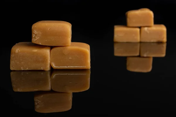 Sladký karamelové cukroví izolovaný na černém skle — Stock fotografie