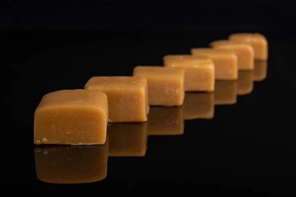 Süße Karamellbonbons isoliert auf schwarzem Glas — Stockfoto