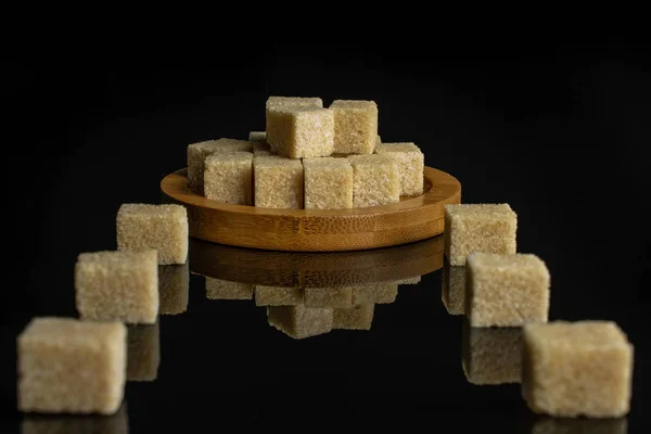 Brown sugar cube isolated on black glass