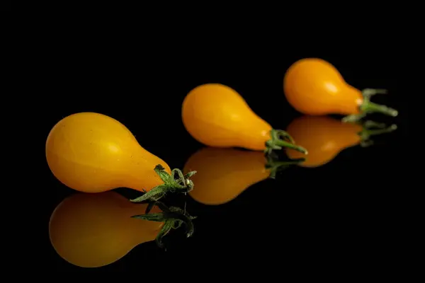 Yellow pear tomato isolated on black glass — Stock Photo, Image