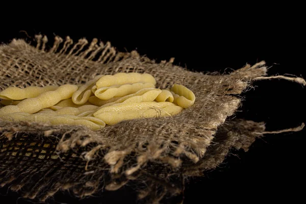 Rohe Cavatelli-Pasta isoliert auf schwarzem Glas — Stockfoto