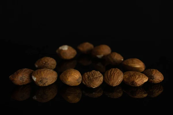 Brown almond nut isolated on black glass — Stock Photo, Image