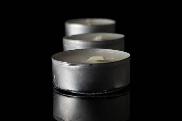 Waxy tea candle isolated on black glass