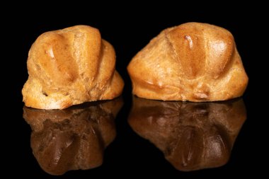 Altın fırınlanmış profiterol siyah camda izole edilmiş.