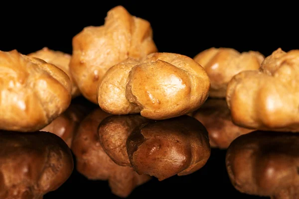 Gouden gebakken profiterole geïsoleerd op zwart glas — Stockfoto