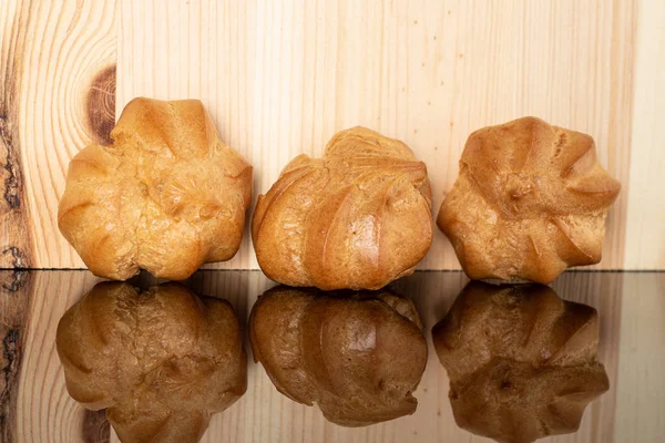 Gouden gebakken profiterole op glas met hout — Stockfoto