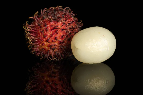 Rambutan vermelho fresco isolado em vidro preto — Fotografia de Stock