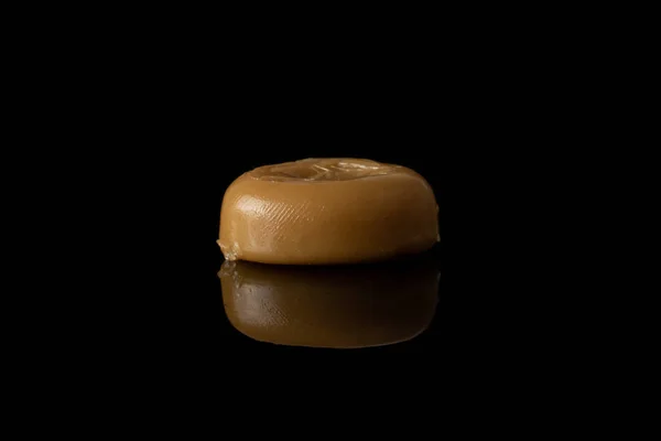Коричневі карамельні цукерки ізольовані на чорному склі. — стокове фото