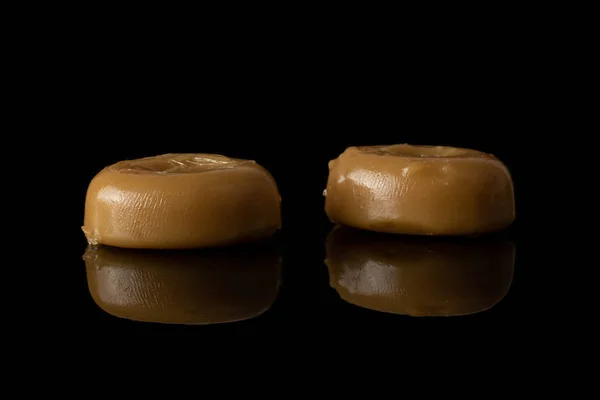 Brown caramel candy isolated on black glass