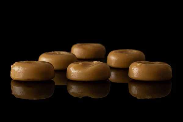 Brown caramel candy isolated on black glass