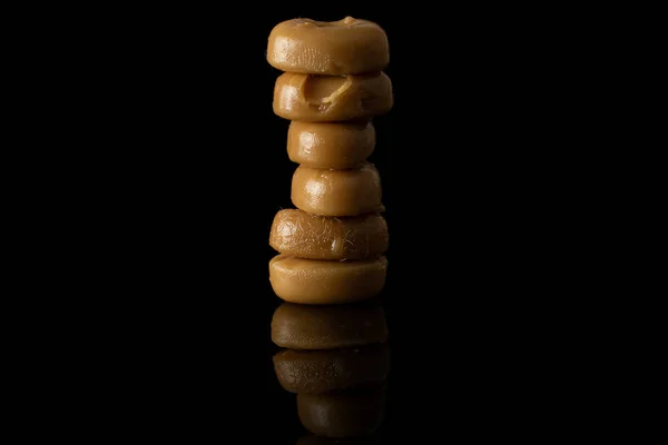 Hnědé karamelové bonbóny izolované na černém skle — Stock fotografie