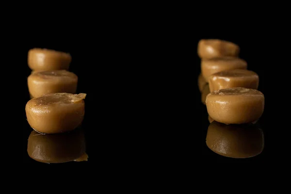 Brown caramel candy isolated on black glass — Stock Photo, Image