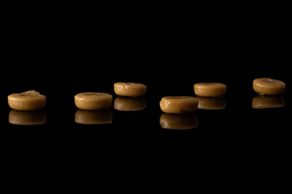 Bruin karamel snoep geïsoleerd op zwart glas — Stockfoto
