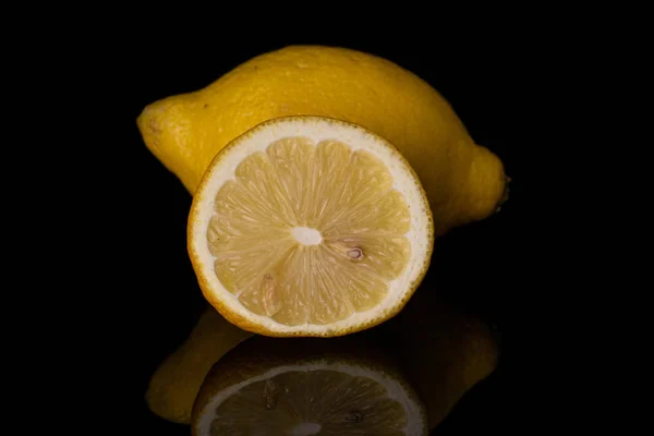 Fresh yellow lemon isolated on black glass — Stock Photo, Image