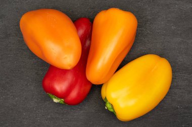 Gri taşın üzerinde dört taze biberlik bir grup.