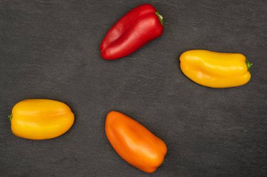 Gri taşın üzerinde dört taze biberlik bir grup.