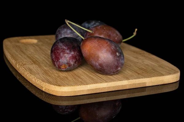 Sweet purple plum isolated on black glass