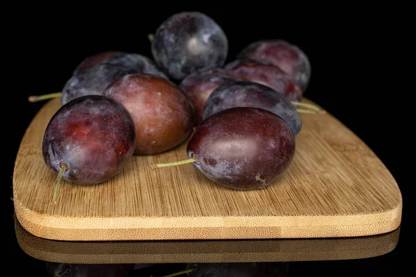 Sweet purple plum isolated on black glass