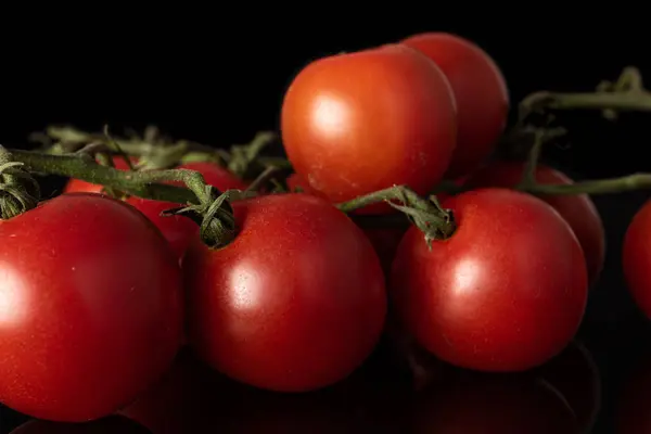 Frische rote Tomate isoliert auf schwarzem Glas — Stockfoto