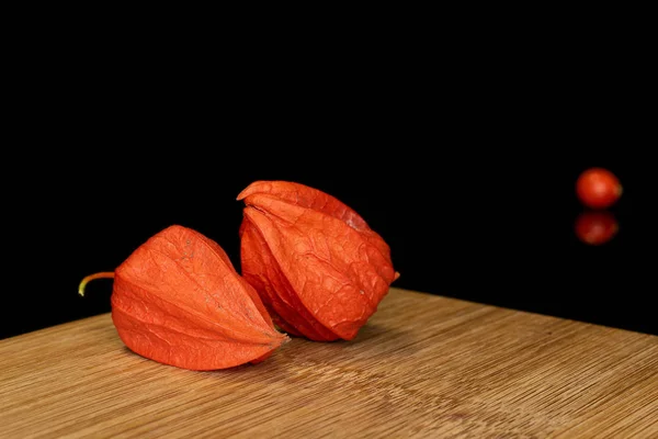 Frische orange Physalis isoliert auf schwarzem Glas — Stockfoto