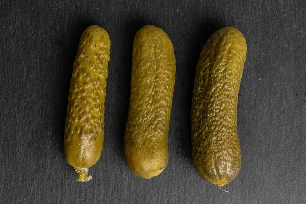 Sura gröna pickles på grå sten — Stockfoto