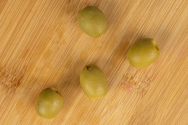 Grün marinierte Oliven auf hellem Holz — Stockfoto
