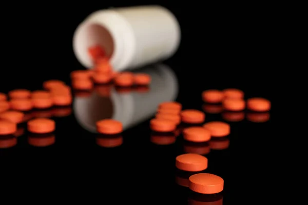 Tableta de farmacia naranja aislada en vidrio negro —  Fotos de Stock