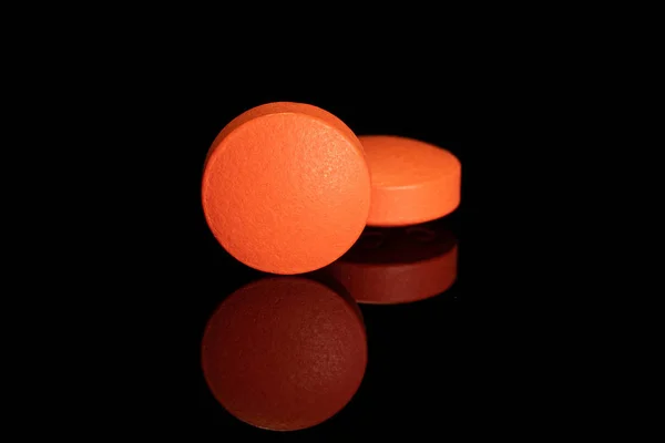 Tableta de farmacia naranja aislada en vidrio negro — Foto de Stock