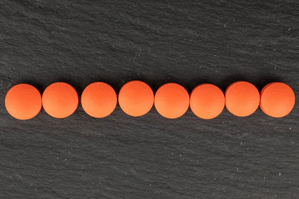 Pomarańczowa tabletka farmaceutyczna na szarym kamieniu — Zdjęcie stockowe