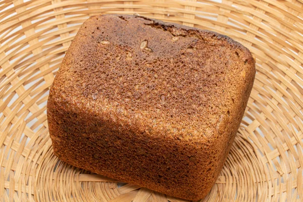 Świeży pieczony ciemny chleb na plecionym rattanie — Zdjęcie stockowe