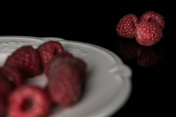 Fresh crimson raspberry isolated on black glass — Stock Photo, Image