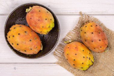 Gri ahşap üzerinde taze turuncu opuntia.