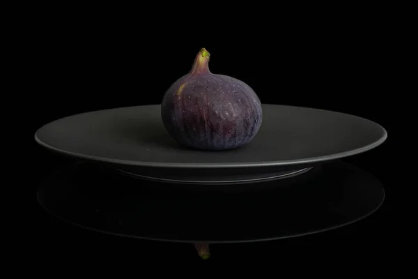 Fresh purple fig isolated on black glass