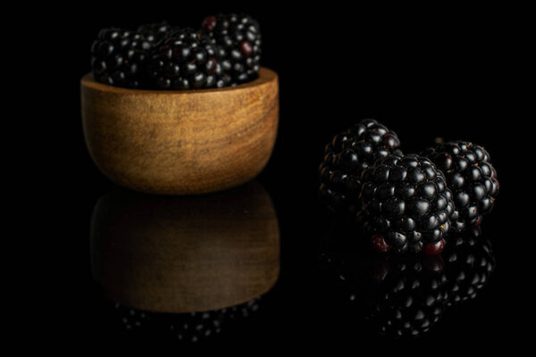 Fresh black blackberry isolated on black glass