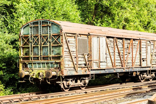 Vários vagões enferrujados e trem nas trilhas — Fotografia de Stock