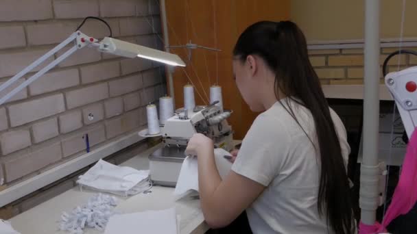 Las trabajadoras de una fábrica de prendas de vestir con máscaras médicas en la cara cosen máscaras protectoras durante la pandemia del virus COVID-19. Lucha contra la pandemia de COVID-19 . — Vídeos de Stock