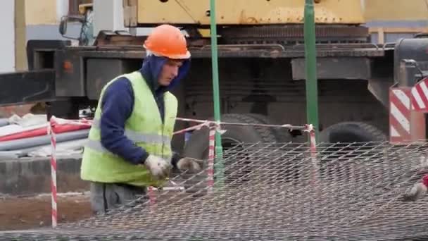 Группа рабочих-мужчин в желтых желе и касках несут металлическую сетку для заливки бетона . — стоковое видео