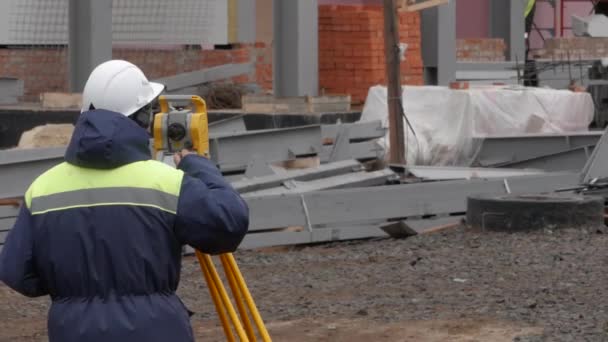 Мужчина измеряет расстояние на строительной площадке с помощью лазерного дальномер . — стоковое видео
