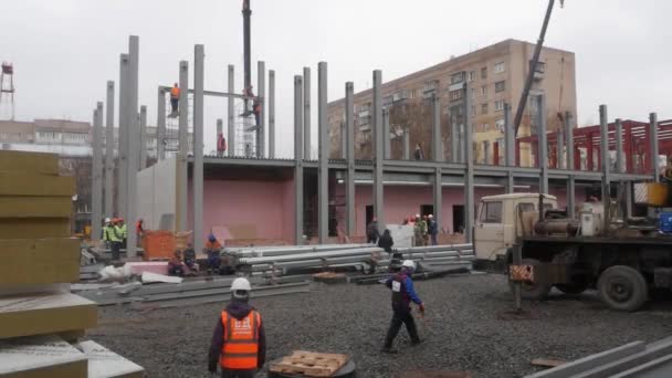 Un grupo de trabajadores masculinos con chaquetas y cascos amarillos está en el sitio de construcción . — Vídeo de stock