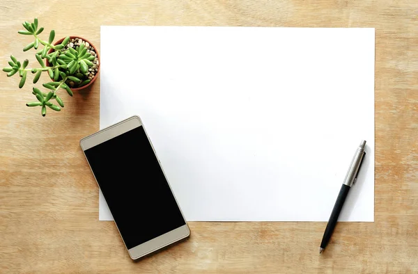 Vista superior da mesa de escritório com caneta, telefone inteligente e branco pa — Fotografia de Stock