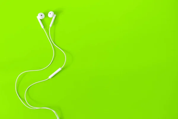 Top view of White Earphones on green background. Copy space. Music is my life concept