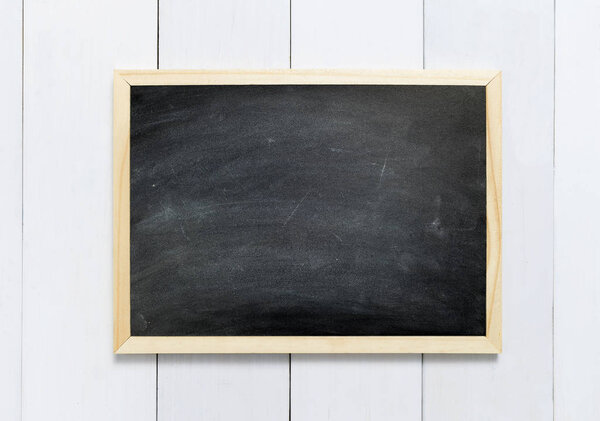 Blackboard / chalkboard texture. Empty blank black chalkboard with chalk traces on white wood table