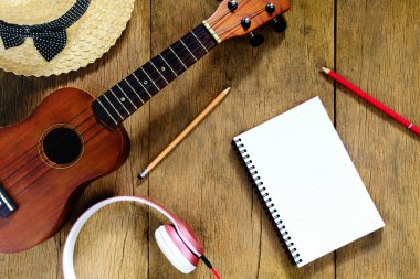 Üst görünüm ahşap masa, orada dizüstü bilgisayarlar, kalemler, şapka, kulaklıklar, ve ahşap masa üzerinde ukulele, gevşeme çekimleri. Müzik konsepti
