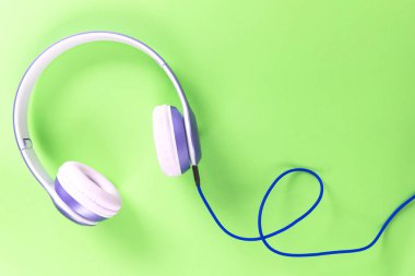Pastel renkli yeşil arka planda mor kulaklık ve mavi kablo. Müzik konsepti. Boş kopya alanı