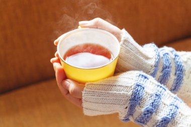 Seçici odak ve yumuşak odak/kadın elleri fincan sarı çay sıcak tutarak, bir kış Ile