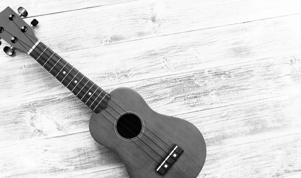 O ukulele preto e branco no fundo da mesa de madeira branca, espaço de cópia em branco. Conceito musical — Fotografia de Stock