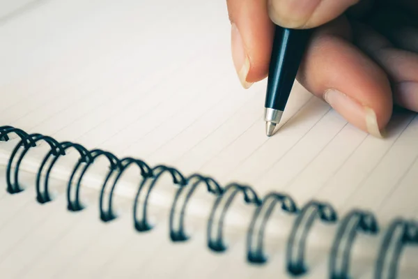 Mano de mujer con bolígrafo escrito en cuaderno blanco. Concéntrate en la punta de la pluma que se está escribiendo. con espacio de copia —  Fotos de Stock