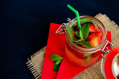  Buzlu çilek kokteyli ve siyah ve kırmızı arka planda nane şekeri ve çuval bezi, şık ve lezzetli.